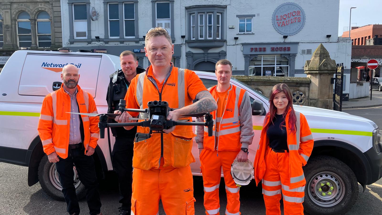 A group of people in orange, one holding a drone