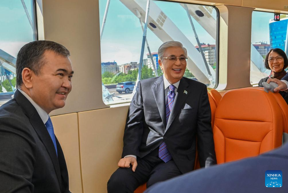 Kazakh President Kassym-Jomart Tokayev (2nd L) takes the light rail on the first day of its operation in Astana