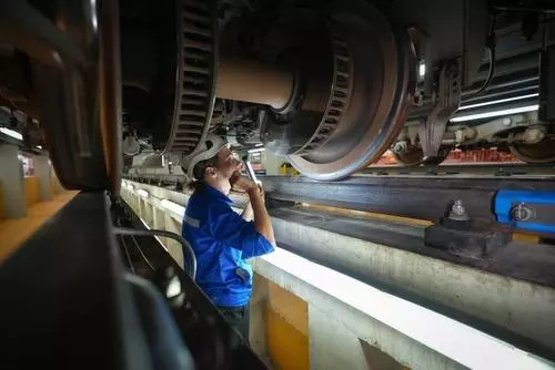 Maintenance man looking underneath a train