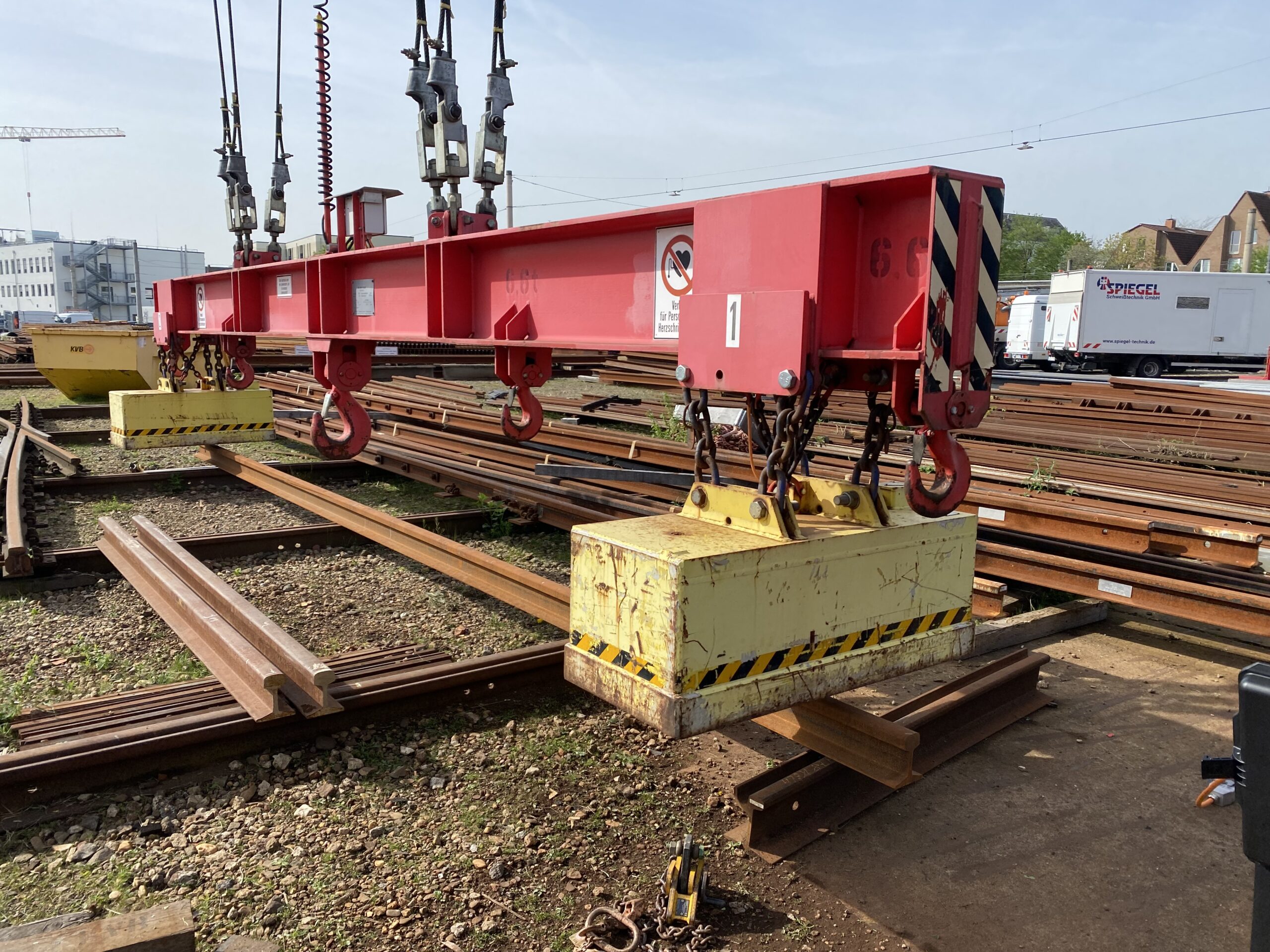 Electromagnetic lifting gear handling rail sections at a rail yard