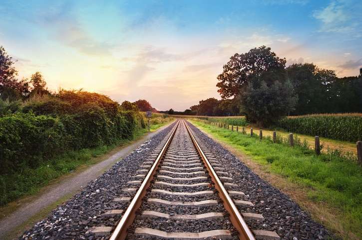 Straight railway track stretching into the distance at sunset, symbolising the track level data foundation behind reliable rail visibility