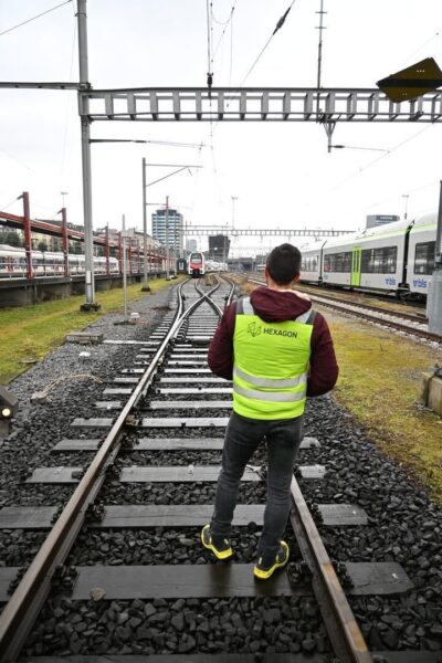 Hexagon engineer in high-vis vest walking along railway tracks at an SBB depot in Switzerland