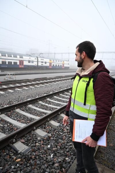 Hexagon CALIPRI technician holding a measurement checklist beside SBB railway tracks in fog