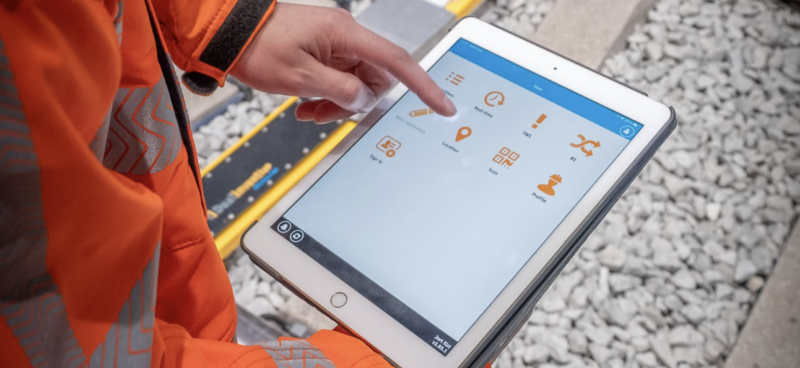 Rail worker in high-visibility clothing using the MTinfo 3000 app on a tablet trackside