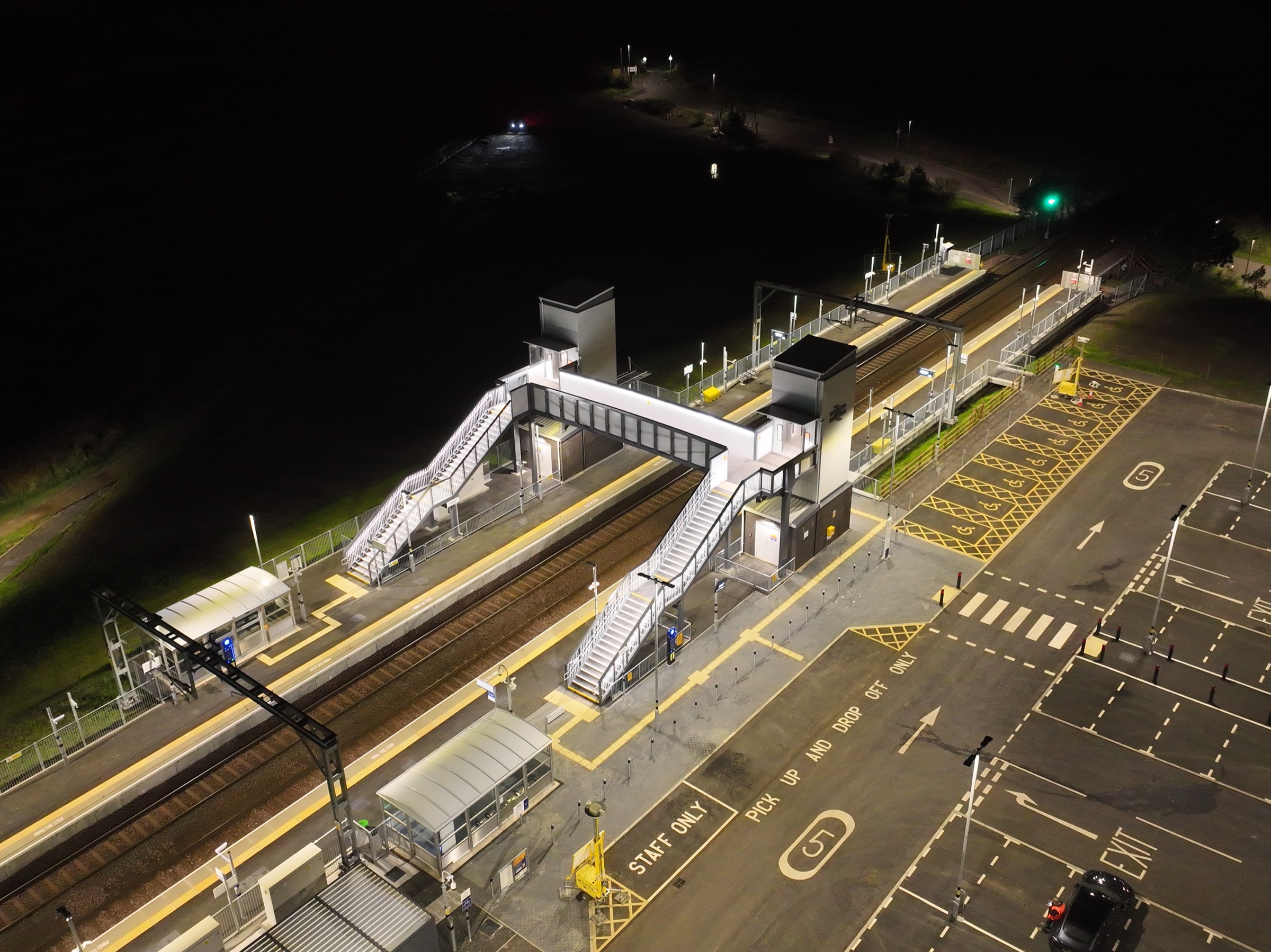 Aerial night view of Balgray Station with its new footbridge lit by linear LED lighting