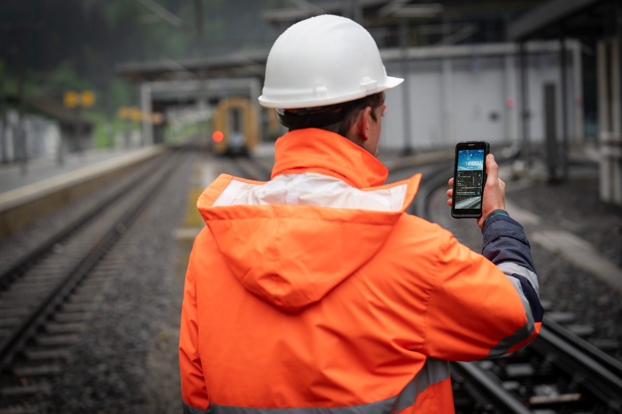 Railway worker on a station platform using a handheld mission-critical communications device