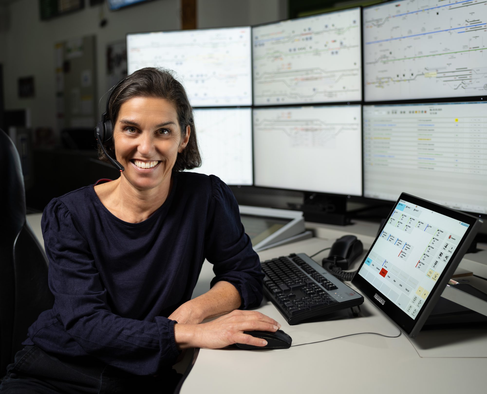 Railway dispatcher at a control room workstation with signalling overview displays behind