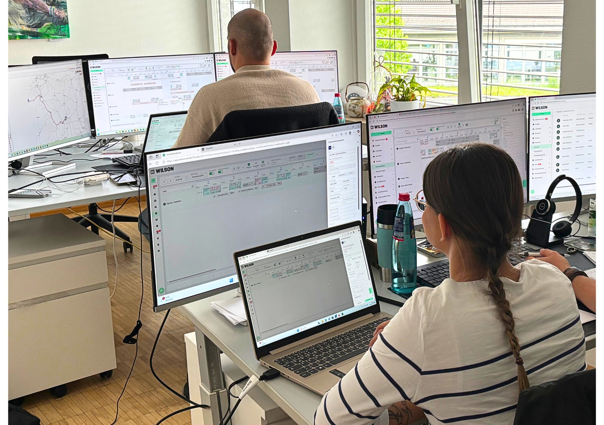 Two Menlo79 staff at desks with multiple monitors running the WILSON workforce planning software