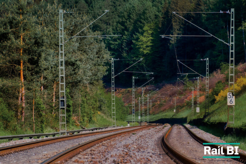 Rail infrastructure planning data visualised against a backdrop of weather-affected track, representing climate resilience planning for rail networks