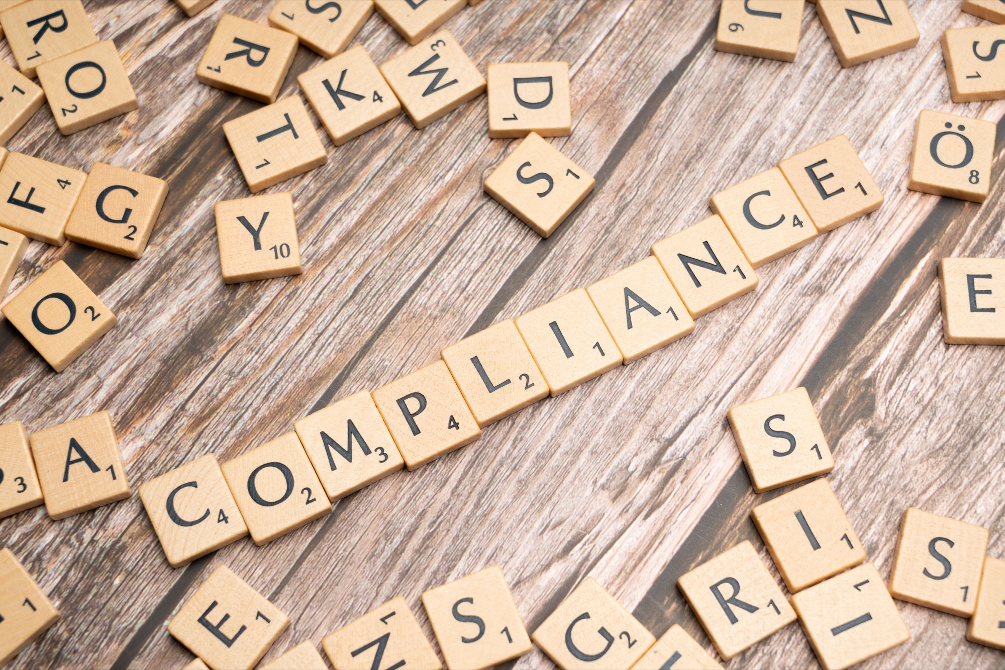 Wooden letter tiles spelling the word compliance