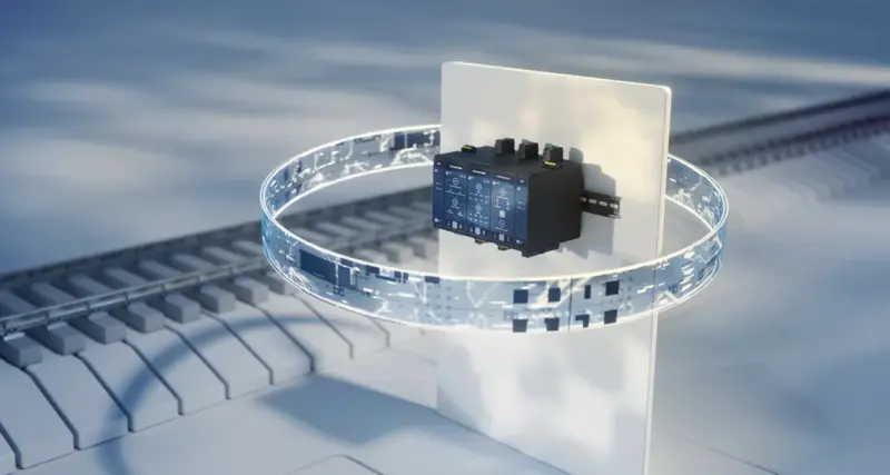 Rendered illustration of a row of compact, dark grey rail-mounted controller modules on a white panel, encircled by a glowing ring of digital circuit patterns, with a stylised railway track in the background.