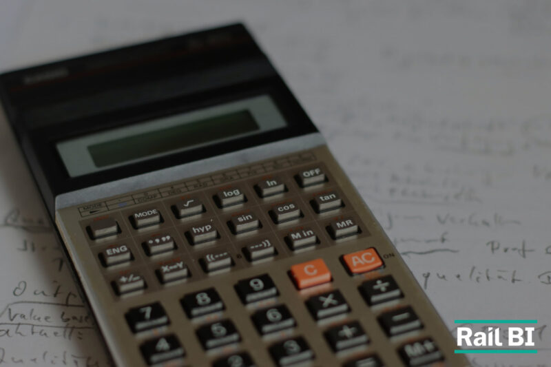 A scientific calculator resting on a sheet of handwritten notes, with the Rail BI logo in the bottom right corner, illustrating bottom-up rail cost estimation that connects asset evidence, assumptions and risk to stronger infrastructure business cases