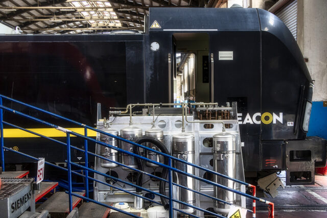 Black Beacon Rail-liveried Siemens Vectron locomotive 191-023 in SŽ – VIT's Ljubljana workshop, with removed equipment including air reservoirs and pipework on a stand in the foreground, during its first full in-house overhaul