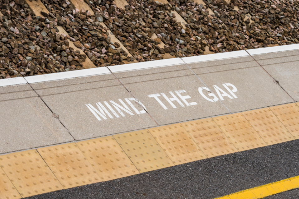 A 'MIND THE GAP' sign sprayed on a platform edge